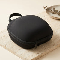 The soft contoured carry case for the Luxuel Laser Cap 272 — a cap-shaped zip case in matte black fabric with a webbing carry strap